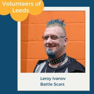 Leroy Ivanov, smiling in front of an orange wall, Volunteers of Leeds feature for Battle Scars, volunteering in Leeds.