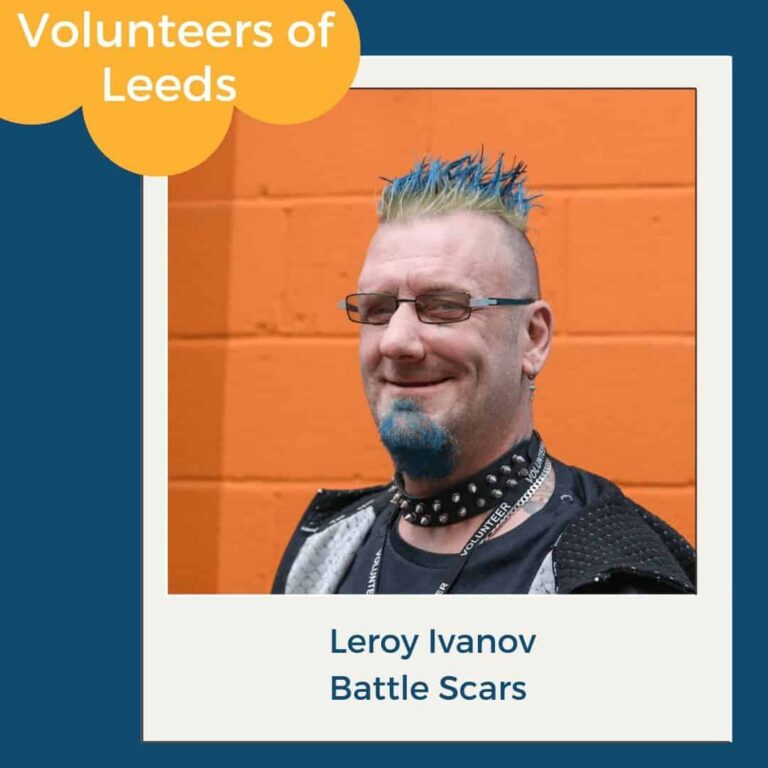 Leroy Ivanov, smiling in front of an orange wall, Volunteers of Leeds feature for Battle Scars, volunteering in Leeds.
