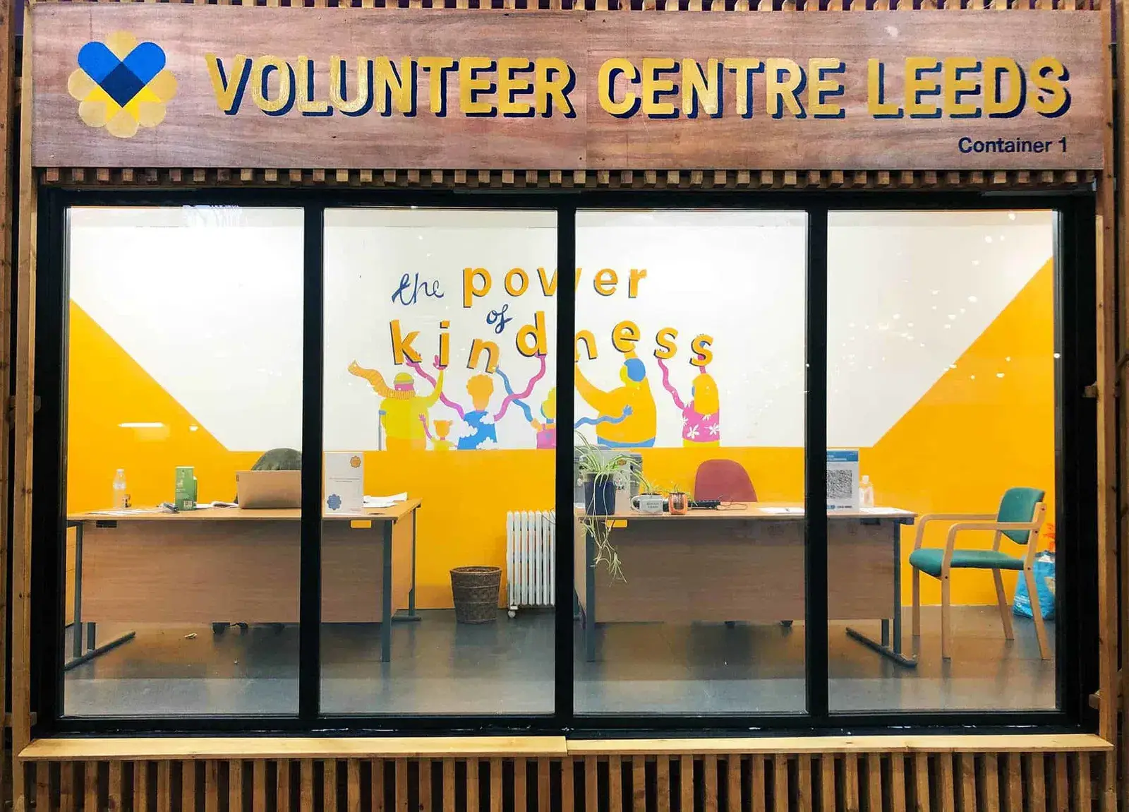 Volunteer Centre Leeds office with desks and mural saying "the power of kindness." Volunteering hub in Leeds, Doing Good Leeds.