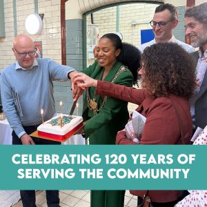 People smile and cut a candlelit cake in Leeds, marking 120 years at Bramley Baths with a community share offer celebration.