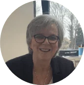 Smiling older woman in glasses sits in Leeds office, representing Young Lives Leeds and youth advocacy.